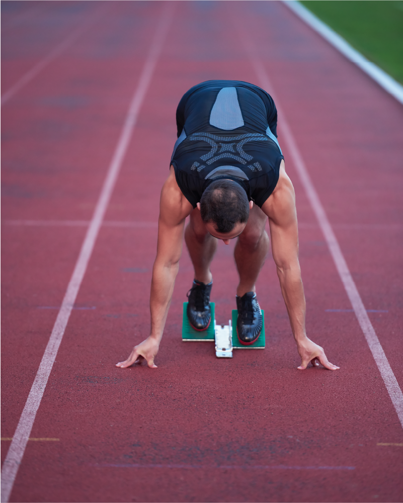 photo of man at starting block on a track
